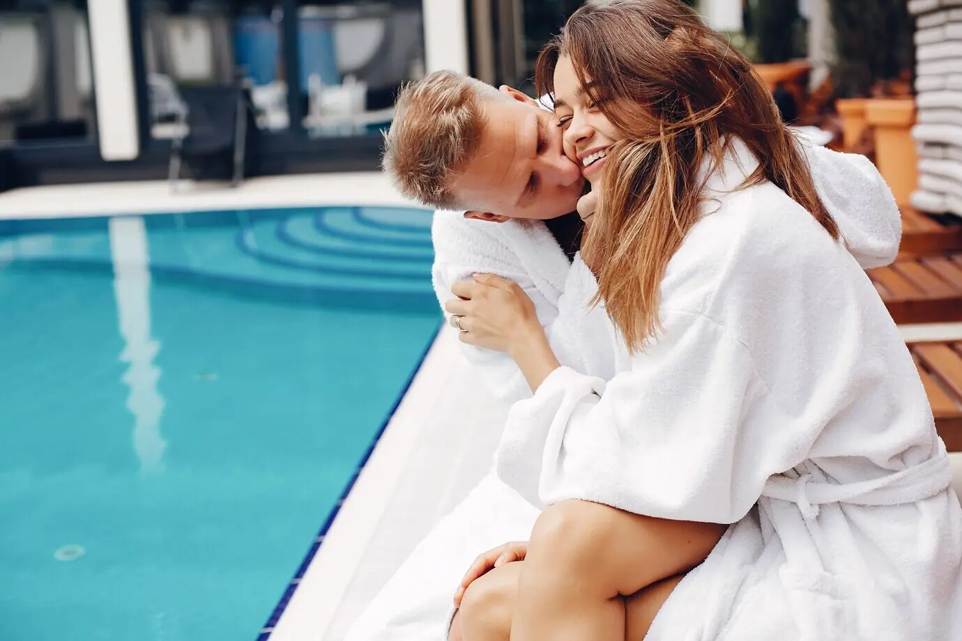 Ein elegantes Paar sitzt in der Nähe eines Swimmingpools.